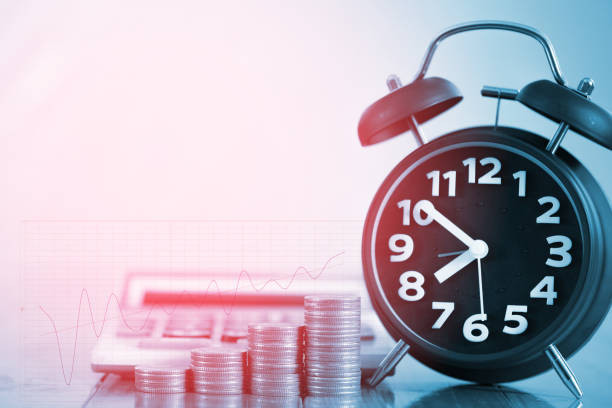 istock Alarm clock and step of coins stacks on working table with financial graph, time for savings money concept. 870641028
