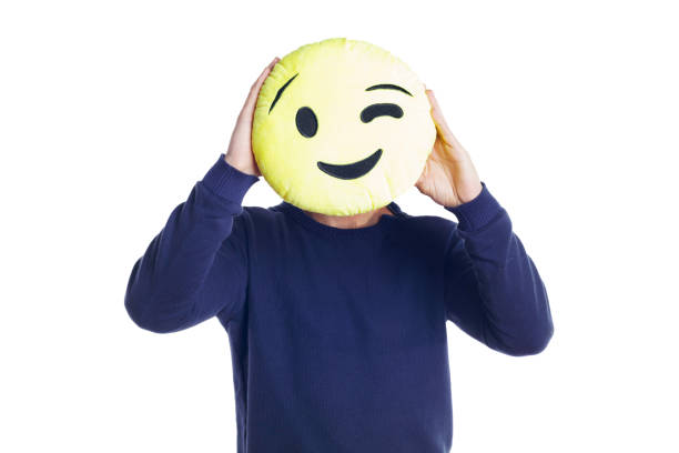 istock Man holding a winking emoji plush. 870644678