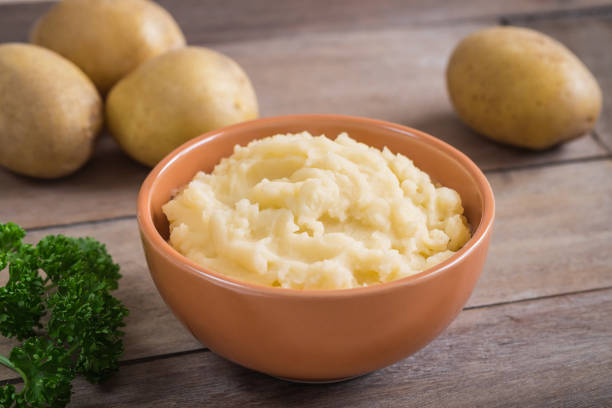 istock Mashed potato in bowl and fresh potatoes on wooden table 870655198