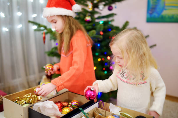 istock Two adorable little sisters decorating a Christmas tree 870668080
