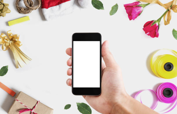istock Hand holding mobile smart phone, blank white vertical screen on white background with Christmas and Valentines decoration 870687912
