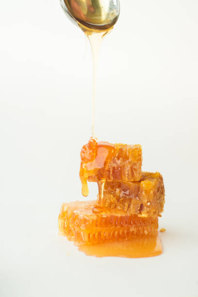 istock Honey stream flowing from spoon on honeycombs 870701032