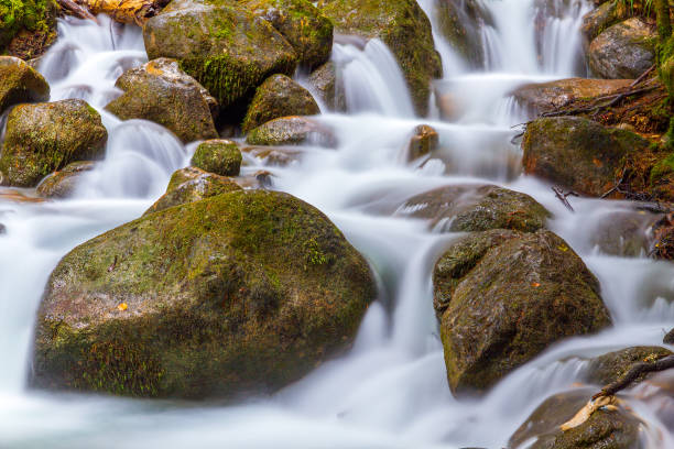 istock Nature detail: water stream which goes among big stones. 870701320