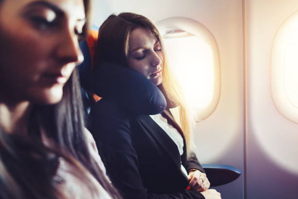 istock Two businesswomen sleeping in the airplane using neck cushion while going on business trip 870703898