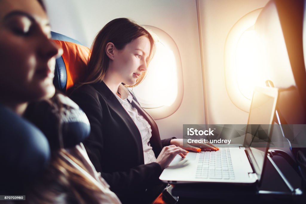 Unternehmerin, die Arbeiten am Laptop sitzt in der Nähe von Fenster in einem Flugzeug - Lizenzfrei Flugzeug Stock-Foto