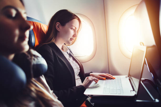 female entrepreneur working on laptop sitting near window in an airplane - business class imagens e fotografias de stock