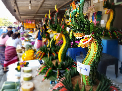 Colorful naga sculpted flower Kratongs for sale at Chiang Mai's colorful flower market by the Mae Ping River in the center of town. In Thailand there is a famous yearly festival called Loy Kratong, this generally occurs in early November, where people traditionally float a colorful Kratong or floatable wreath into rivers, lakes and waterways. They are adorned with flowers, candles and incense sticks, people launch these to make merit to the spirits of water with a belief of good luck brought to them for the coming year. The floats are normally launched at night creating a spectacle of light, while fireworks, lanterns and decorative parades are held across the Kingdom.
