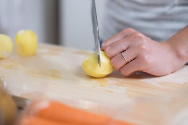 pommes de terre de coupe de femme au foyer dans la cuisine - stereotypical homemaker photos et images de collection