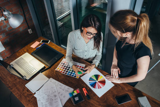 two creative female designers choosing colors working with colour palette in the office - interior designer imagens e fotografias de stock