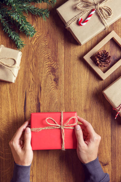 istock Man Hands holding craft paper gift box on table wood decoration. 870718406