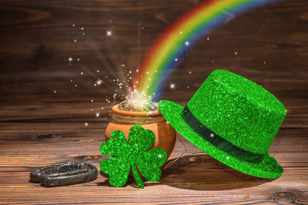 St Patricks day decoration with magic light rainbow pot full gold coins, horseshoe, green hat and shamrock on vintage wooden background, close up St Patricks day decoration with magic light rainbow pot full gold coins, horseshoe, green hat and shamrock on vintage wooden background, close up st. patricks day photos stock pictures, royalty-free photos & images