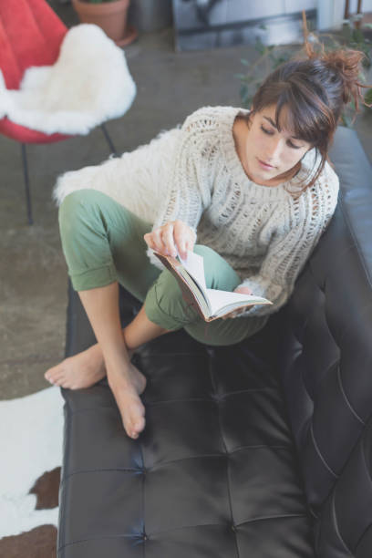 istock Woman lying on a sofa and reading a book 870726328