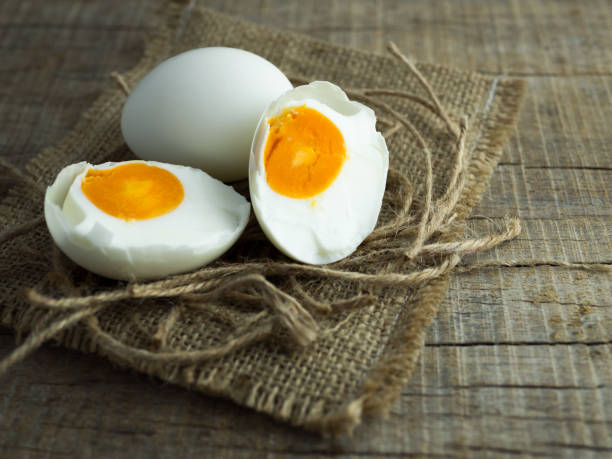 Duck eggs, white eggs, salted eggs with yolk on old sack and ropes with wooden background.