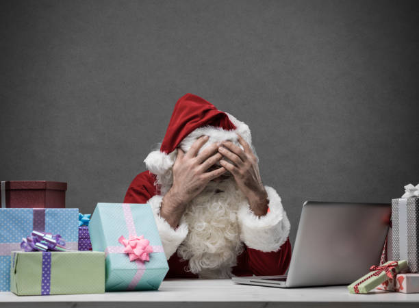 babbo natale stressato che si connette con il suo laptop - holiday emotional stress christmas santa claus foto e immagini stock