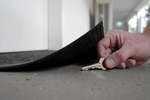 Man picking up or hiding a key under the door mat A man's hand is picking up or returning key under the door mat key doormat stock pictures, royalty-free photos & images
