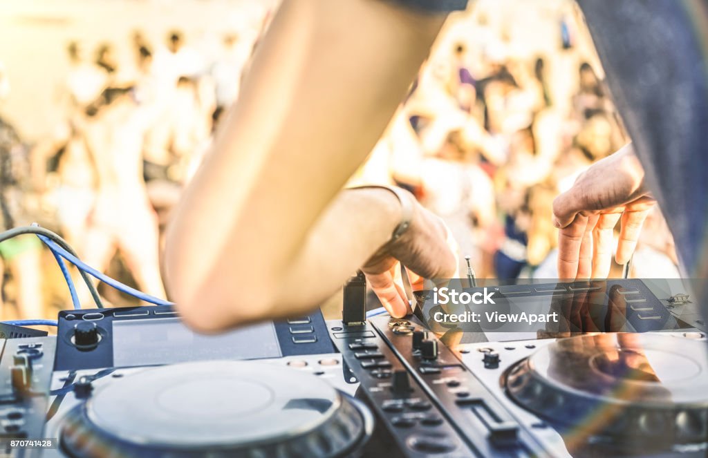 Close up of dj playing electro sound on modern cd usb player at summer beach party - Music festival and entertainment concept  - Defocused background with shallow depth of field - Focus on mixing hand DJ Stock Photo