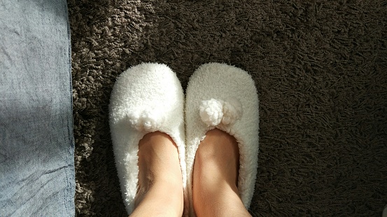 feet wearing slippers on carpet in the morning
