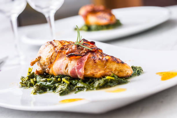 istock Chicken grill breast. Chicken roasted breast with bacon and spinach on white plate. Culinary food  in hotel pub or restaurant 870749392