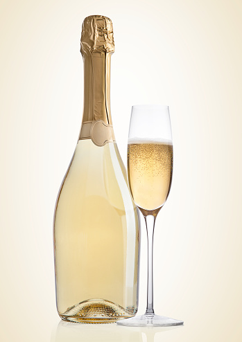 Bottle and glass of yellow champagne on yellow background