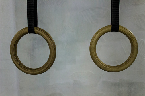 Athletics rings against a light wall background