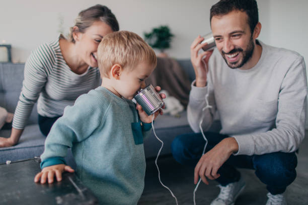 Using our Tin Can Phone Photo of a young family using tin can telephone toy phone stock pictures, royalty-free photos & images