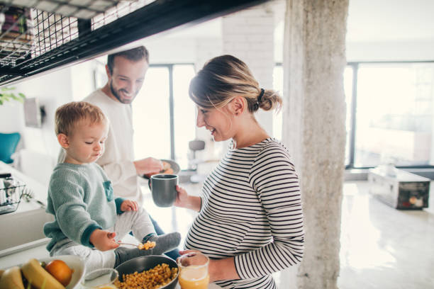 Crowdy in our kitchen Photo of a young family preparing breakfast together in their kitchen young family stock pictures, royalty-free photos & images