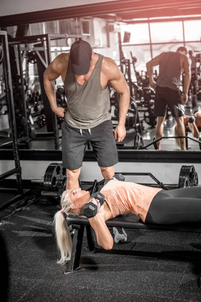 istock Female dumbbell chest press with help of personal trainer 870780246
