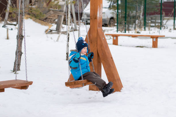 istock Happy child on swings at a winter park 870780512