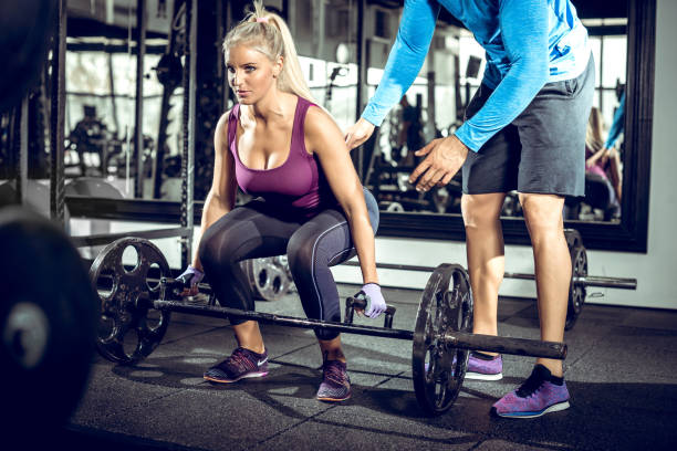 Trap bar deadlift woman with personal trainer Attractive blonde woman doing trap bar deadlift exercise with help of her personal trainer. Toned image. blonde female bodybuilders stock pictures, royalty-free photos & images