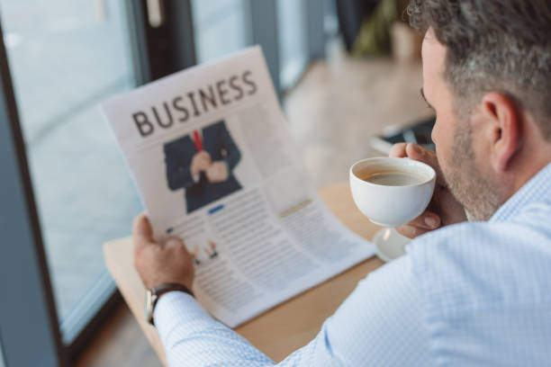 istock businessman drinking coffee and reading newspaper 870785190