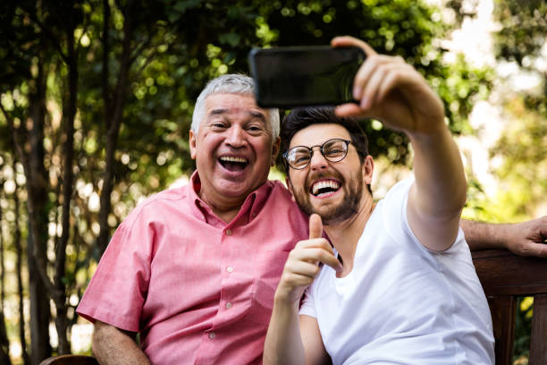 papà e figlio si fanno selfie e si divertono nel parco - grandparent family multi generation family technology foto e immagini stock