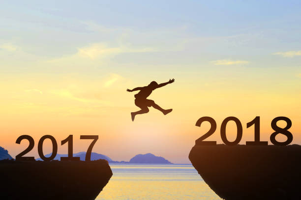 istock Men jump over silhouette Happy New Year 2018 870807684