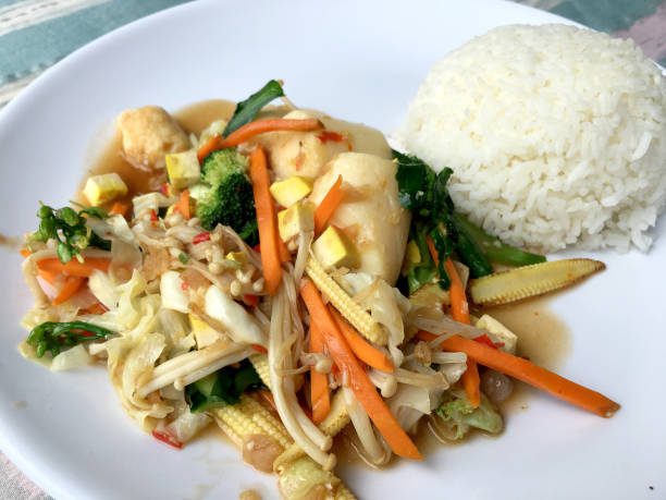 istock Stir tofu with mixed vegetables Chinese Style in white dish with rice on table. low fat healthy food for Vegetarian Festival. 870824150