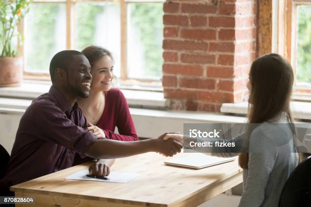 Young Multiethnic Couple Shaking Hands With Real Estate Agent Stock Photo - Download Image Now