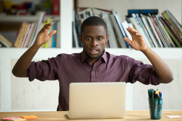 Shocked african american office worker looking at laptop screen.