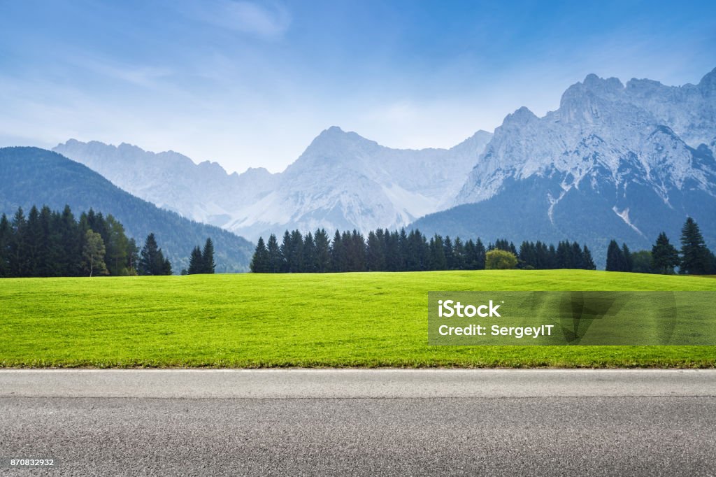 Asphalt road and green meadow alps mountains on background Road Stock Photo