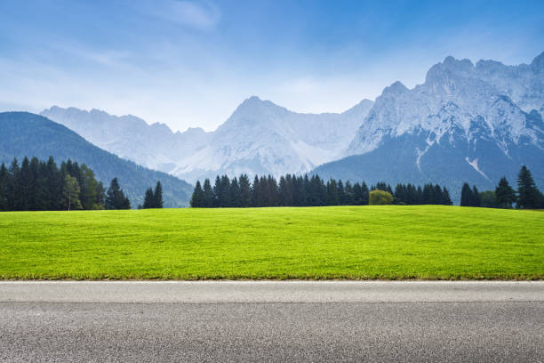 Asphalt road and green meadow alps mountains on background alpine climate photos stock pictures, royalty-free photos & images