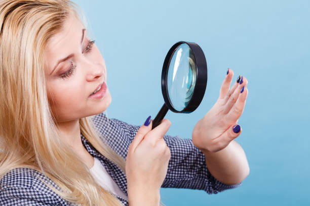 istock Woman looking at nails through magnifying glass 870842608
