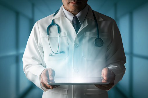 Medical Healthcare Concept - Doctor in hospital looking at tablet computer.