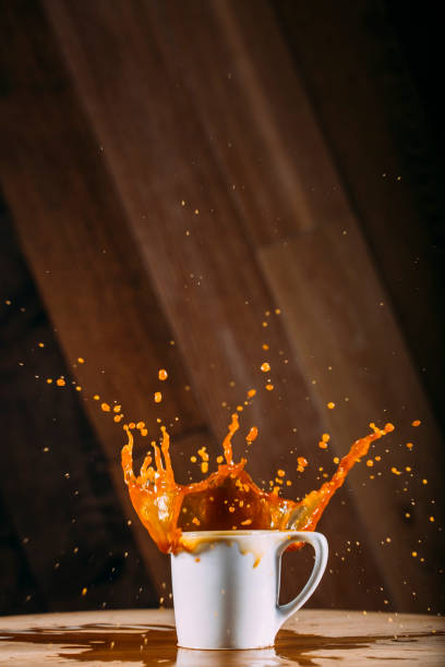 istock Coffee spilling out of white cup on a wooden table 870850988