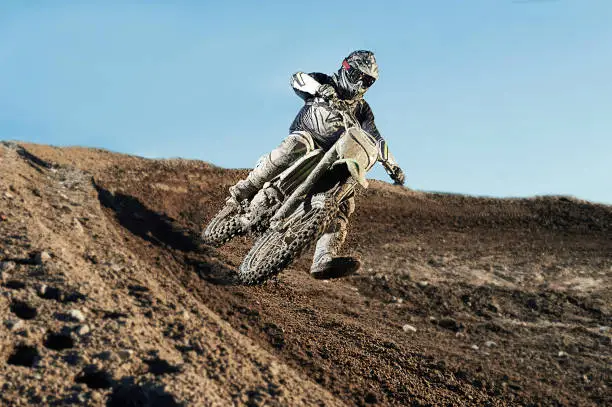 Motocross driver in action accelerating the motorbike after the corner on the race track