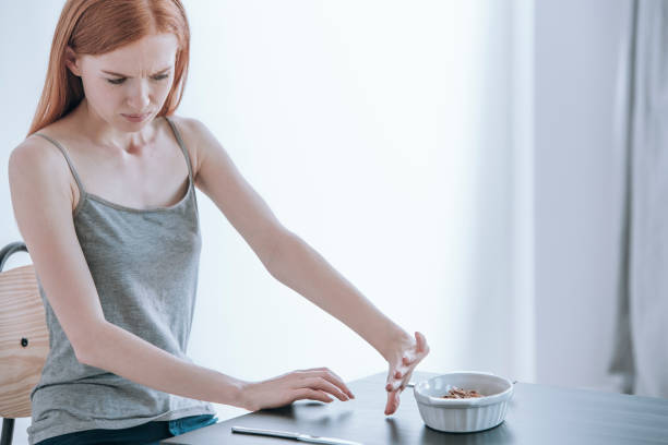Depressed girl with eating disorder Young depressed girl at table with food in bowl. Eating disorders concept self destructive stock pictures, royalty-free photos & images