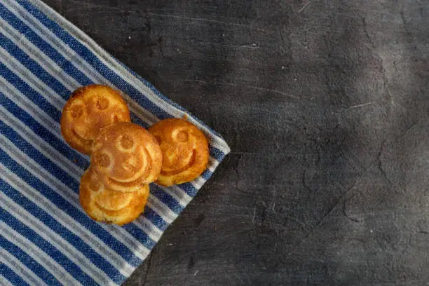 Sweet cookies with a smile, lie on a towel with blue strips. Concrete background. Copy space