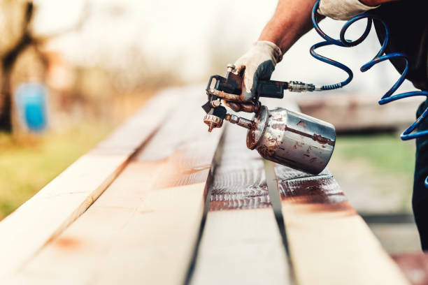 istock Industrial handyman, construction worker painting with spray gun on site. Construction details 870879086