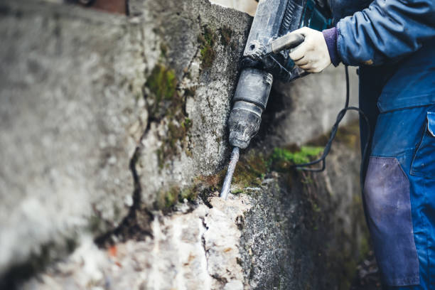 istock worker man using a jackhammer to drill into wall. professional worker in construction site 870884118