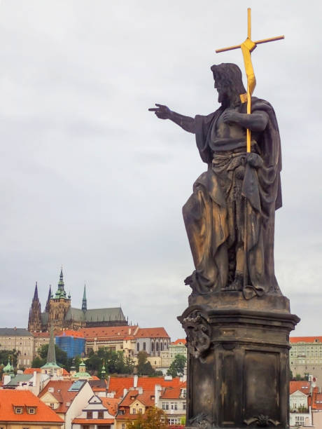 istock Statue on St. Charles Bridge Points to Castle and Town in Distance 870887220