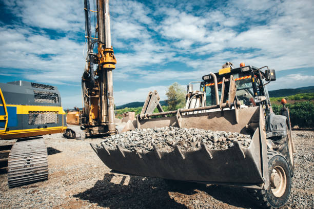 istock Industrial heavy duty bulldozer moving gravel on highway construction site. Multiple industrial machinery on construction site 870887724