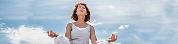 femme d’yoga vieillissement magnifique avec un ciel bleu, longue bannière - senior adult outdoors wellbeing sky photos et images de collection