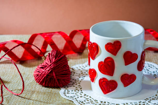 istock composition for st valentine's day with an hart made by a red rope, a white cup with a lot of harts and a red ribbon 870894812