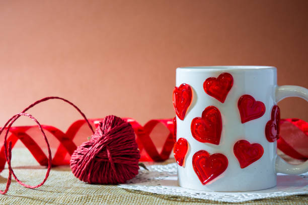 istock composition for st valentine's day with an hart made by a red rope, a white cup with a lot of harts and a red ribbon 870894820